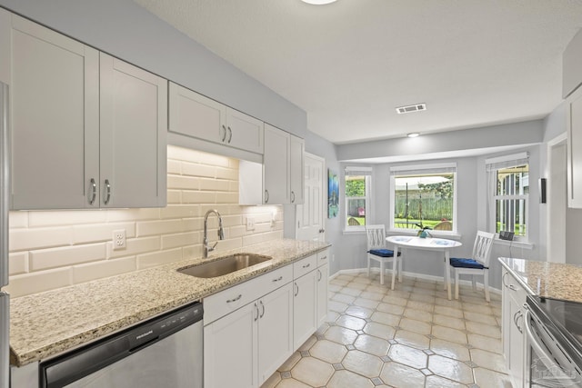 kitchen with a sink, stainless steel appliances, tasteful backsplash, visible vents, and white cabinetry