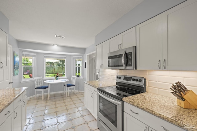 kitchen featuring visible vents, stainless steel appliances, decorative backsplash, and white cabinets