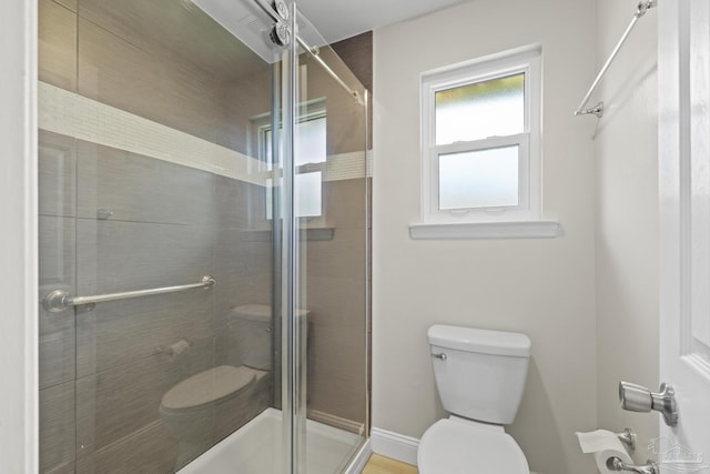 bathroom featuring toilet and a shower stall