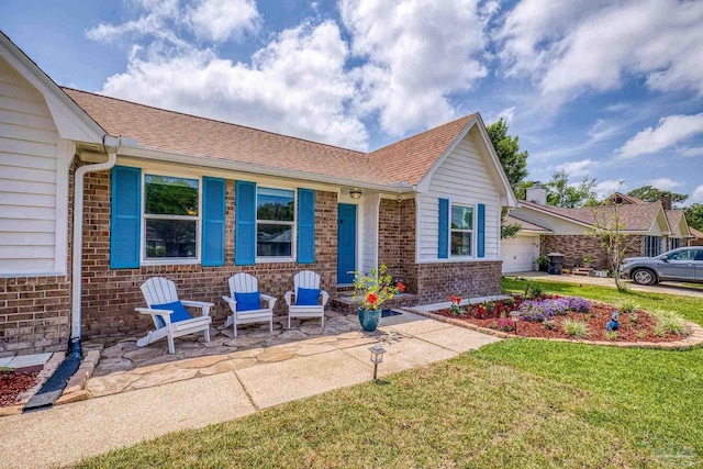 view of front of home featuring a front lawn, roof with shingles, a garage, and brick siding