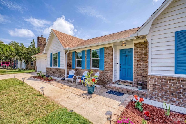 view of front of home featuring a porch, a garage, brick siding, a chimney, and concrete driveway