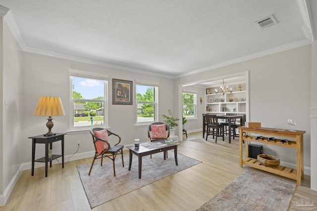 sitting room featuring ornamental molding, a textured ceiling, a chandelier, and light wood-type flooring