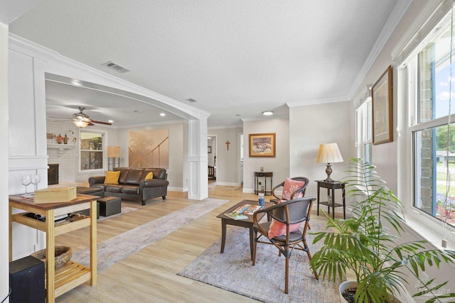 living area with crown molding, visible vents, baseboards, light wood-type flooring, and a fireplace