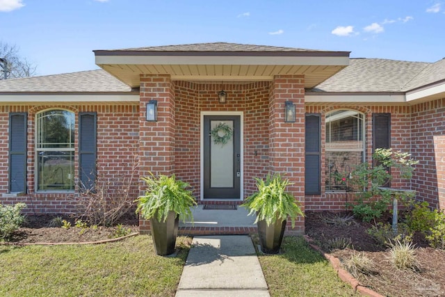 doorway to property with brick siding and roof with shingles