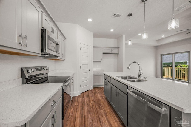 520 K St, Pensacola, FL 32501 - kitchen featuring stainless steel appliances, a sink, gray cabinetry, dark wood-type flooring, and a center island with sink