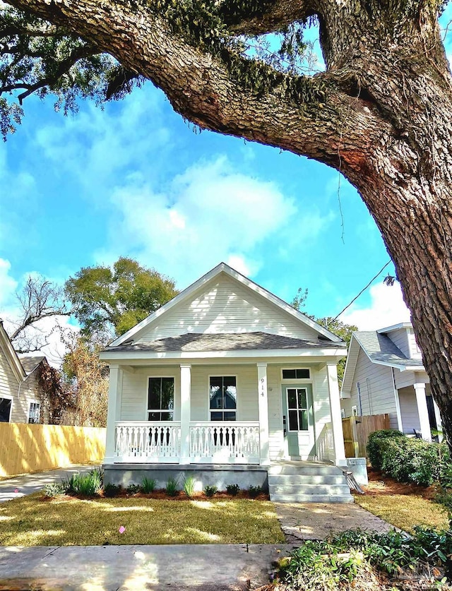 view of front of home with a porch and fence