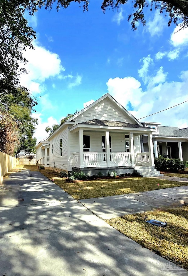 view of front of property featuring concrete driveway, a porch, and fence