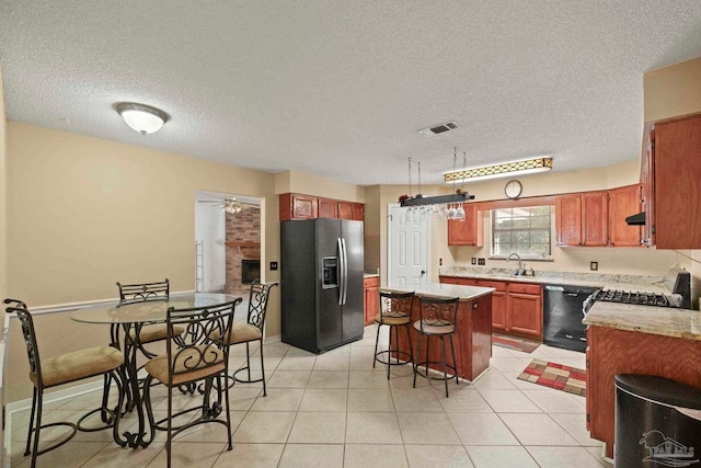 kitchen featuring stainless steel refrigerator with ice dispenser, a kitchen breakfast bar, a textured ceiling, black dishwasher, and a kitchen island