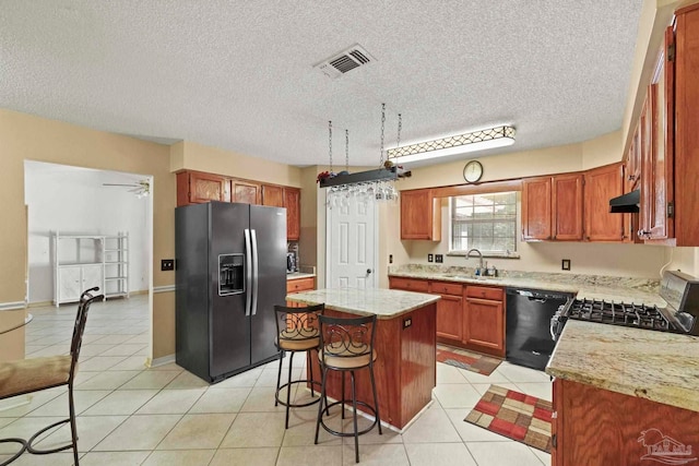 kitchen featuring sink, ceiling fan, a textured ceiling, appliances with stainless steel finishes, and a kitchen island