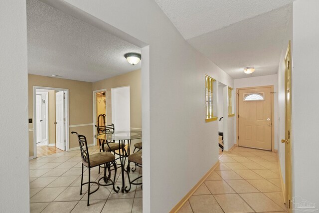 hallway featuring light tile patterned floors and a textured ceiling