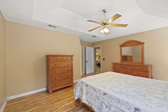 bedroom with ceiling fan, light hardwood / wood-style flooring, and a textured ceiling