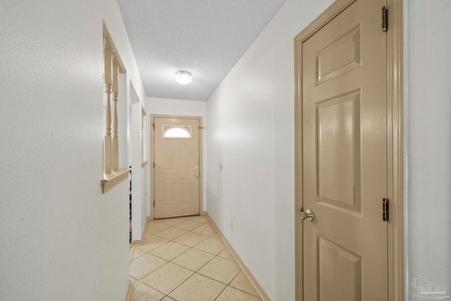 doorway with light tile patterned flooring and a textured ceiling