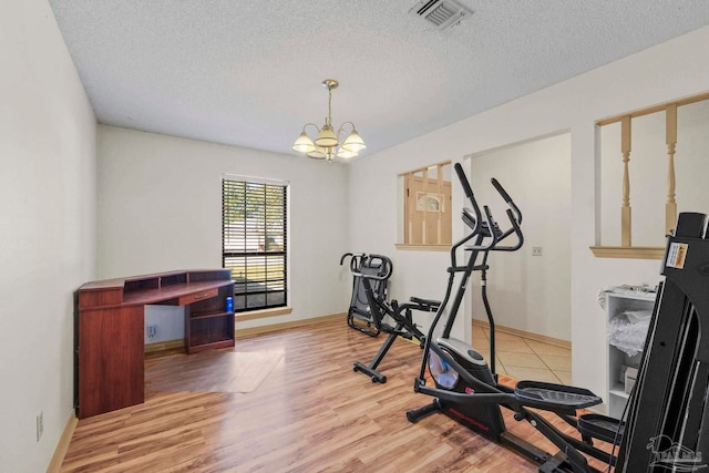 exercise room with a chandelier, wood-type flooring, and a textured ceiling