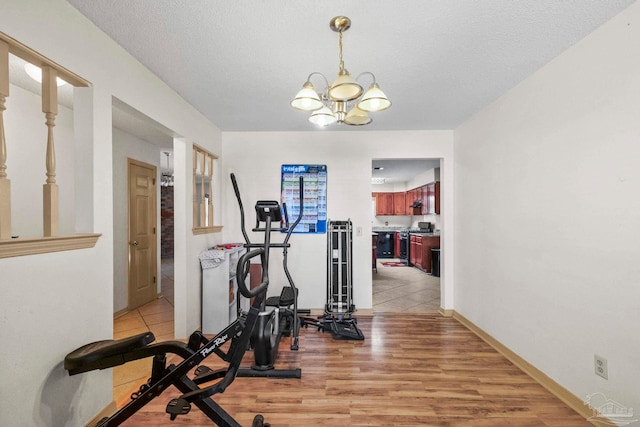 exercise area with hardwood / wood-style flooring, a textured ceiling, and a chandelier