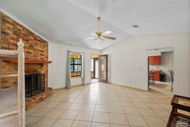 unfurnished living room featuring a brick fireplace, a textured ceiling, ceiling fan, light tile patterned floors, and lofted ceiling