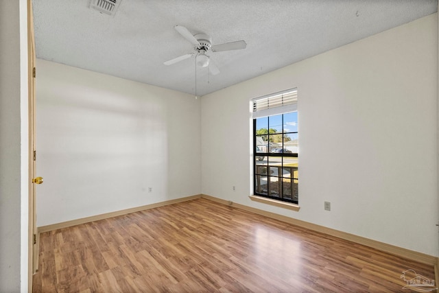 empty room featuring a textured ceiling, light wood-type flooring, and ceiling fan