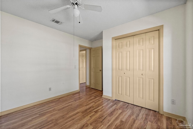 unfurnished bedroom with a closet, ceiling fan, hardwood / wood-style floors, and a textured ceiling