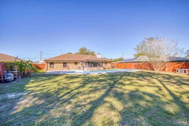 back of house with a lawn, a patio, and an empty pool