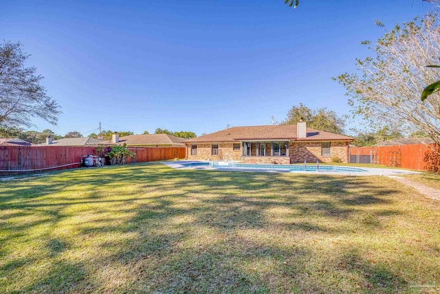 rear view of house with a yard and a fenced in pool