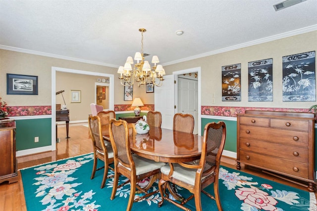 dining room featuring visible vents, wood finished floors, an inviting chandelier, crown molding, and a textured ceiling