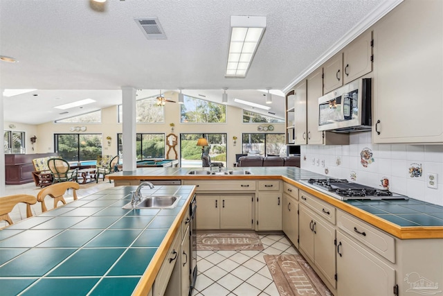 kitchen with tile countertops, stainless steel appliances, open floor plan, and a sink