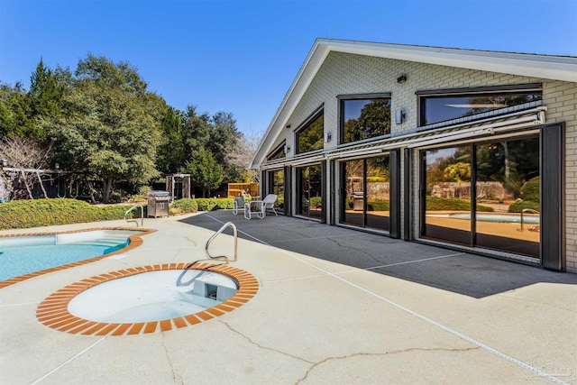 rear view of property featuring a patio area, an outdoor pool, and brick siding