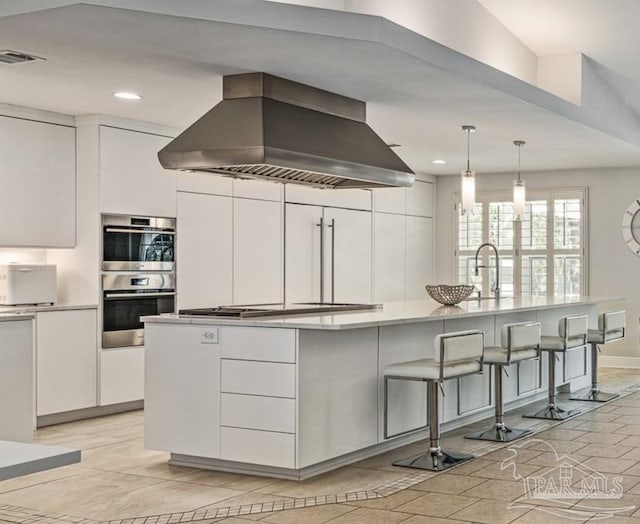 kitchen with visible vents, a kitchen breakfast bar, exhaust hood, white cabinetry, and modern cabinets