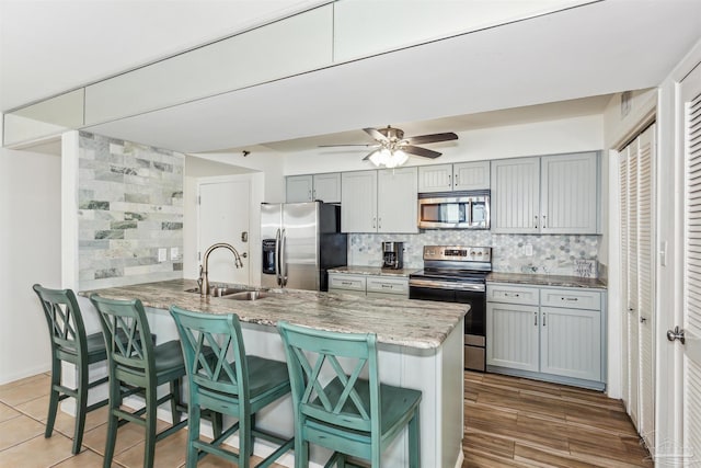 kitchen featuring appliances with stainless steel finishes, a breakfast bar area, ceiling fan, and gray cabinets