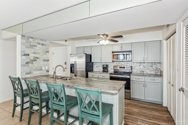 kitchen featuring appliances with stainless steel finishes, a kitchen breakfast bar, kitchen peninsula, ceiling fan, and sink