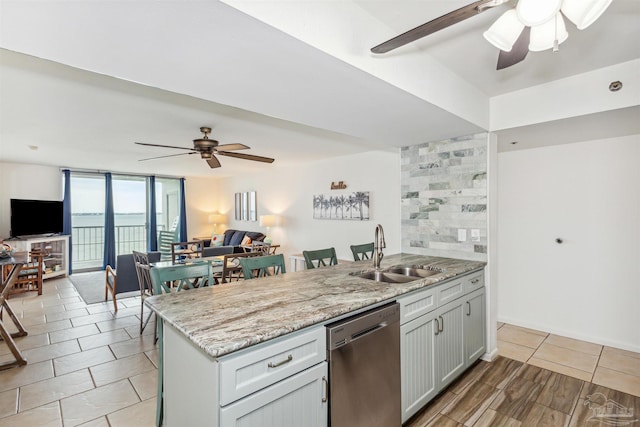 kitchen featuring dishwasher, sink, floor to ceiling windows, light stone countertops, and ceiling fan