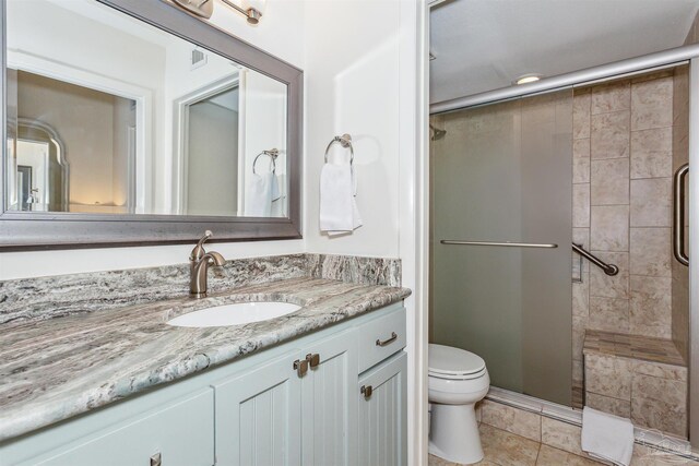 bathroom with vanity, tile patterned floors, a shower with shower door, and toilet