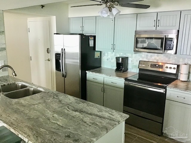 kitchen featuring ceiling fan, light stone countertops, appliances with stainless steel finishes, and sink