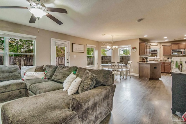 living room with a textured ceiling, ceiling fan with notable chandelier, and dark hardwood / wood-style floors