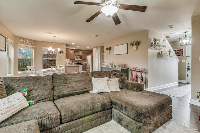 living room with hardwood / wood-style floors and ceiling fan with notable chandelier