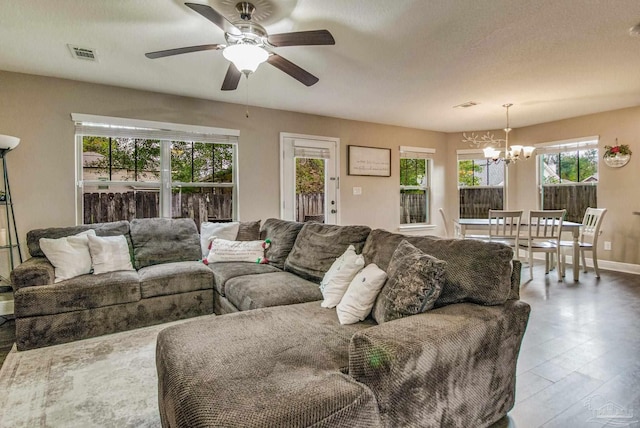 living room featuring a textured ceiling and ceiling fan with notable chandelier