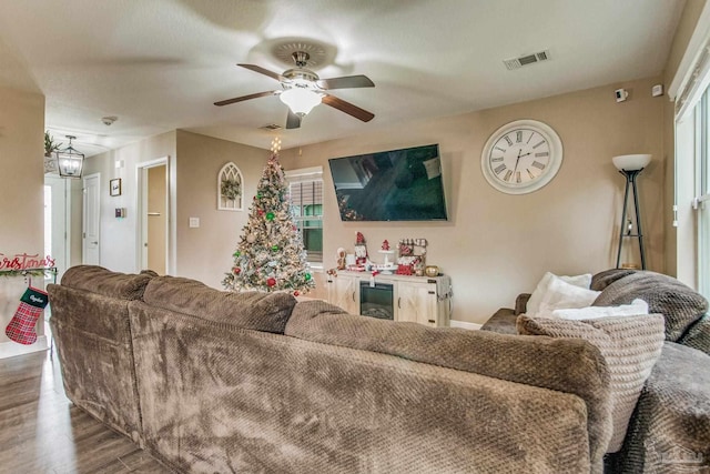 living room featuring ceiling fan with notable chandelier and dark wood-type flooring