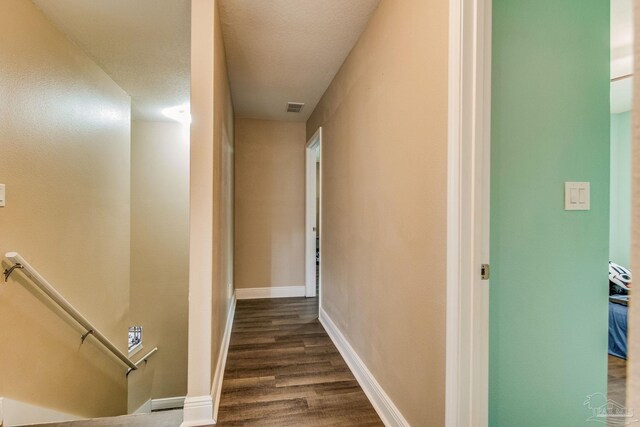 hallway with a textured ceiling and dark wood-type flooring