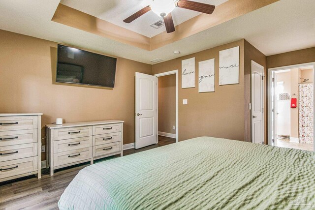 bedroom with a tray ceiling, ceiling fan, and dark hardwood / wood-style flooring