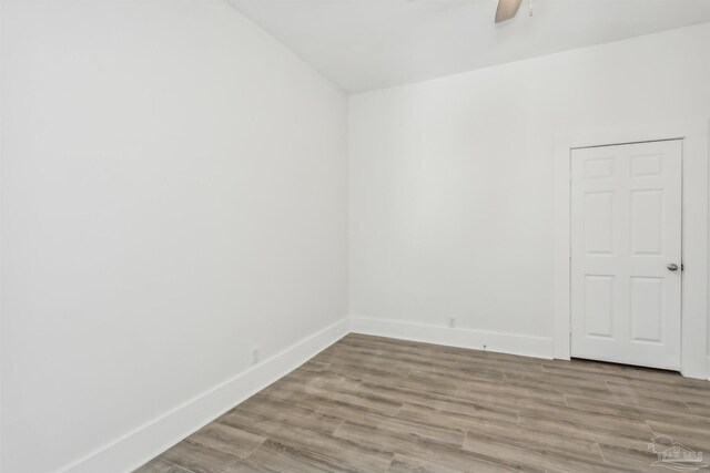 unfurnished bedroom with light wood-type flooring, multiple windows, ensuite bathroom, and ceiling fan