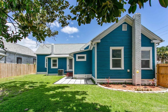 rear view of property featuring central AC unit, a patio, and a lawn