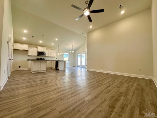 unfurnished living room with ceiling fan, visible vents, baseboards, and wood finished floors