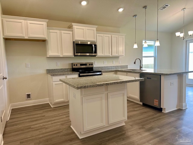 kitchen featuring a kitchen island, appliances with stainless steel finishes, a sink, white cabinets, and a peninsula