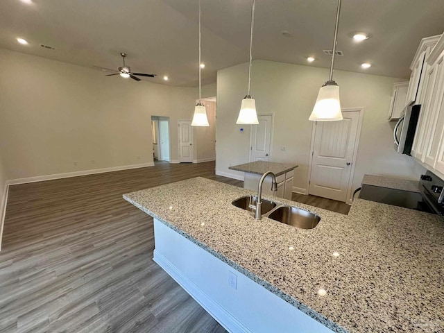 kitchen with a kitchen island, dark wood finished floors, a sink, white cabinets, and stainless steel microwave