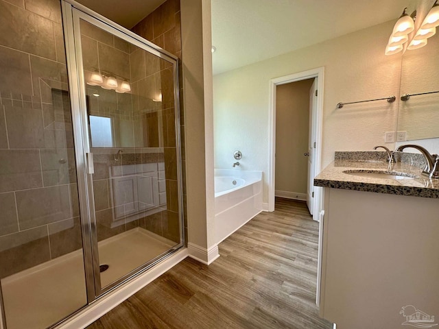 full bathroom featuring a shower stall, wood finished floors, a garden tub, and vanity