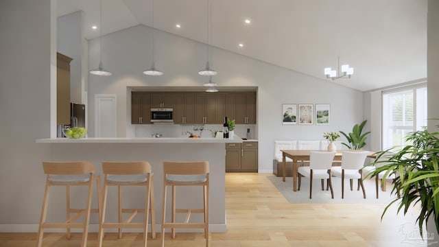 kitchen with appliances with stainless steel finishes, hanging light fixtures, high vaulted ceiling, and light hardwood / wood-style floors