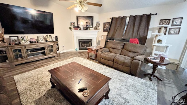 living area with ceiling fan, wood finished floors, and a glass covered fireplace