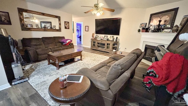 living area featuring ceiling fan, a tile fireplace, and wood finished floors