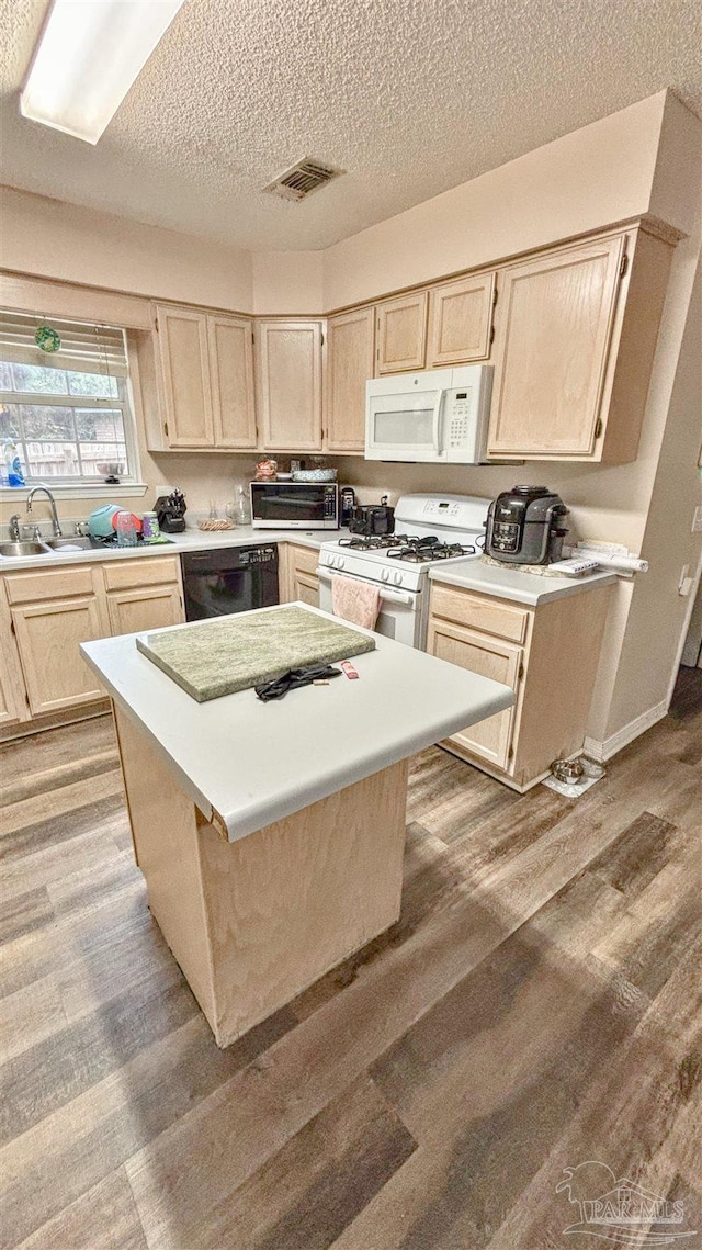 kitchen featuring light brown cabinets, sink, light hardwood / wood-style floors, a textured ceiling, and white appliances