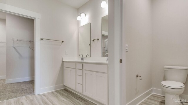 2733 Chevy Cir, Pace, FL 32571 - bathroom with toilet, a spacious closet, vanity, baseboards, and wood finished floors