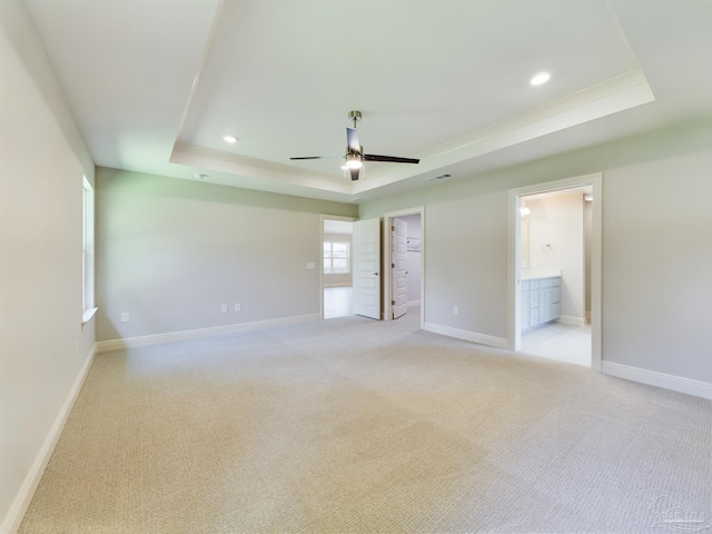 carpeted spare room featuring ceiling fan and a tray ceiling